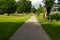 Empty gravel walk path with fresh green trees at day time for background with copy space. Pedestrian zone near lake and hills in