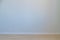 An empty gray wall and a beige background with a white baseboard. Background