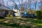 Empty green dumpster with a blue portable potty are seen in a driveway in front of a small house in a residential neighborhood.