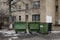 Empty green trash containers with brick wall of a building in background. Russia.