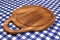 Empty Hardwood Round Cutting Board On The Blue Checkered Tablecloth