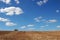 Empty harvested field under cloudy blue sky