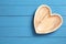 Empty heart shaped wooden plate on blue table, top view. Space for text