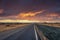 Empty highway amidst volcanic landscape against dramatic sky during sunset