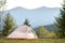 Empty hikers tent standing on campsite with view of majestic high mountain peaks in distance. Camping in wild nature and active