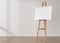 Empty horizontal canvas on wooden easel standing in room. Free, copy space for your picture. Artwork presentation