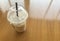 Empty ice coffee plastic cup on window reflection wood table background.