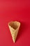 Empty ice cream cone on the red background, top view flat lay. Minimalism style creativity concept