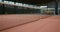 An empty indoor tennis court with a stretched net for play