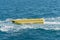 empty inflatable yellow banana boat in the sea. Banana Boat for fun on water surface in summer day - banana boat at the sea