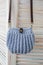 Empty knitted purse hanging on wooden door. Ad and buy concept