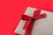 Empty kraft envelope with red ribbon tied in bow on clean red background. Visual content for holiday of lovers. The option of gift