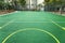 Empty landscaped childrenâ€™s basketball court with green filling