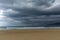 Empty and large beautiful golden sand beach underneath a bad weather sky