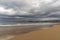 Empty and large beautiful golden sand beach underneath a bad weather sky