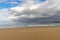 Empty and large beautiful golden sand beach underneath a bad weather sky