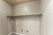 Empty laundry room interior with wall mounted shelf