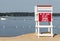 Empty lifeguard stand looking over the calm bay with a boat in the background