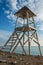 An empty lifeguard tower against the background of the sea and the blue sky with clouds. White wooden lifeguard station