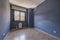 An empty living room with a blue wall, cheap wooden floors and oak door