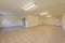 Empty living room of a ground floor residential townhouse with tiled floors, French style windows and white wooden and fire doors