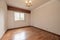 Empty living room with reddish parquet with matching skirting boards and wooden doors with aluminum barred windows and multi-arm
