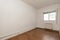 Empty living room with ugly brown tile floors, exposed heating pipes and white aluminum radiators