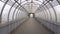 Empty long glass tunnel on the pedestrian bridge, the camera moves through glass tunnel on sunny day with blue sky, at