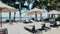 Empty lounge chairs with umbrellas on white sand beach in hot summer day in luxury tropical hotel or resort. Travel