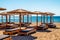 Empty loungers under sunshades on sandy beach with view on sea