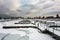 Empty marina with snow covered docks and sheets of ice on cold winter day with overcast sky