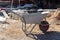 Empty metal wheelbarrow, shovel and other tools at excavation site in Side, Turkey. Ancient ruins in background. Selective focus