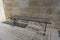 Empty metal wooden benche against beige marble wall. One bench and stone wall background, closeup, copy space