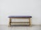 Empty minimal style wooden bench with blue fabric pad and wooden slatted shelf.