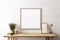 Empty mock up poster frame on white stucco wall above wooden cabinet