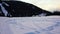 Empty moving cableway lift chairs on the snowy ground and trees at sunset