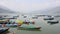 Empty multi-colored wooden boats on the lake Phewa on the background of a misty mountain valley