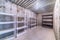 Empty multi layer metal racks inside a storage room with concrete wall and floor