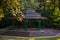 Empty music gazebo in the park - old style summer scene in the shade with sunbeam, trees and green grass