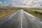 Empty narrow road in beautiful scenery. Burren Area, west of Ireland. Traditional stone fence and cloudy blue sky in the