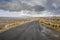 Empty narrow road in beautiful scenery. Burren Area, west of Ireland. Traditional stone fence and cloudy blue sky in the