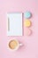 Empty notepad, coffee and colorful macaron on pink pastel desk top view. Cozy morning breakfast. Fashion flat lay.