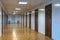 Empty office corridor with many doors of dark red wood.