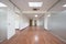Empty offices with technical ceilings, white walls, reddish wooden floors and tempered glass partitions with transparent doors