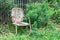 Empty old, weathered chair against a slat fence and greenery, aging death and grief concept