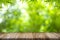 Empty old wooden table top with bamboo leaves frame on blurred greenery background in garden.