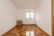 Empty one-story living room with parquet flooring of freshly stabbed and varnished oak slats and white aluminum windows