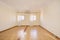 Empty one-story room with two windows with white curtains and light brown tile floors