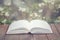 Empty opened book on aged wooden table on fresh jasmine flowers background. Selectve focus