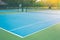 Empty outdoor blue tennis hard court in public park.